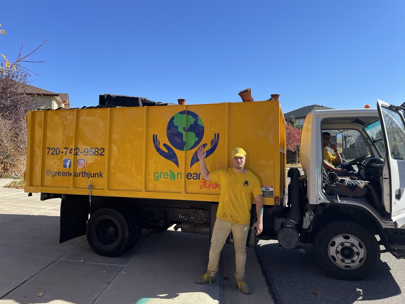 The yellow Green Earth Junk Removal truck parked on a driveway